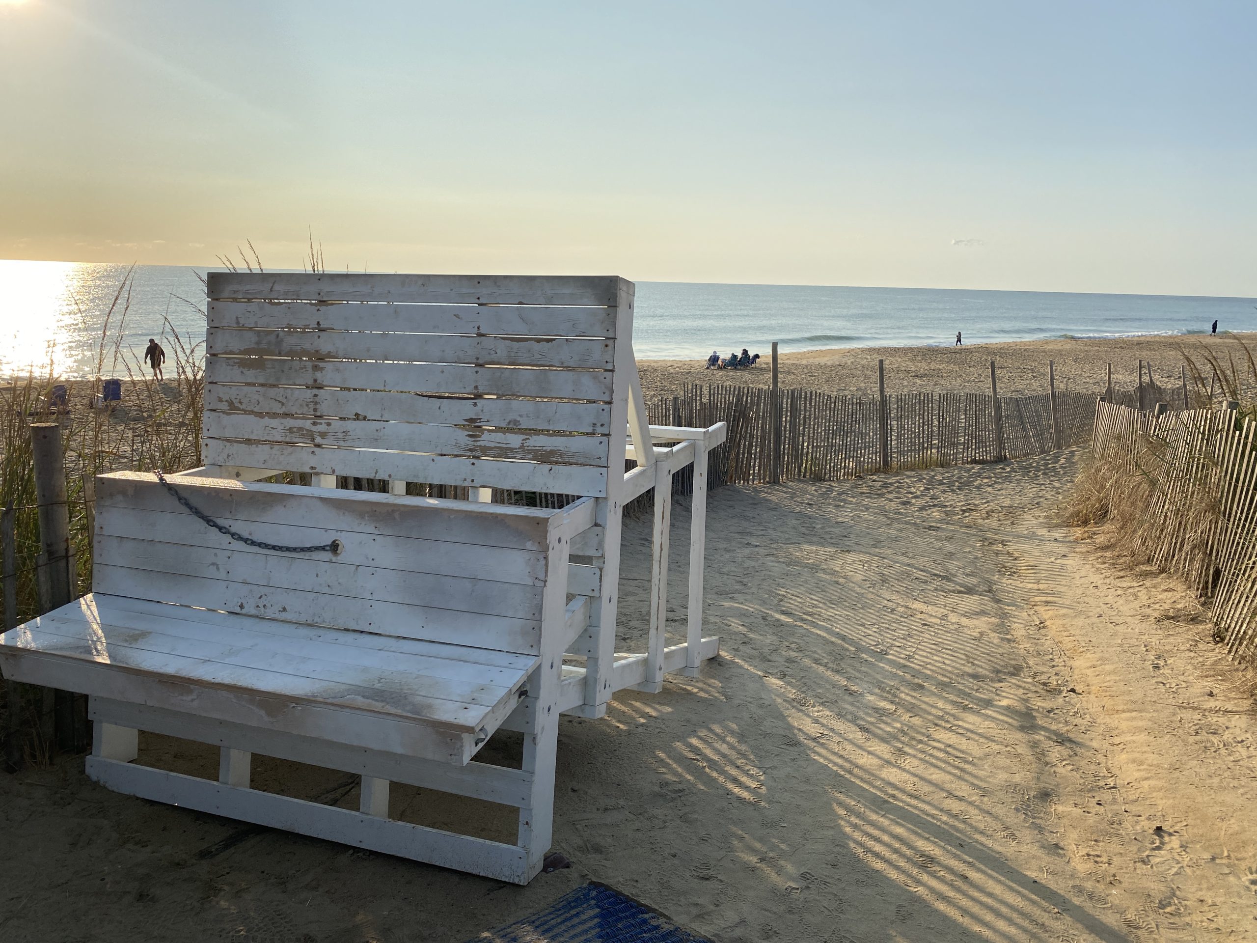 a wooden bench sitting on top of a sandy beach