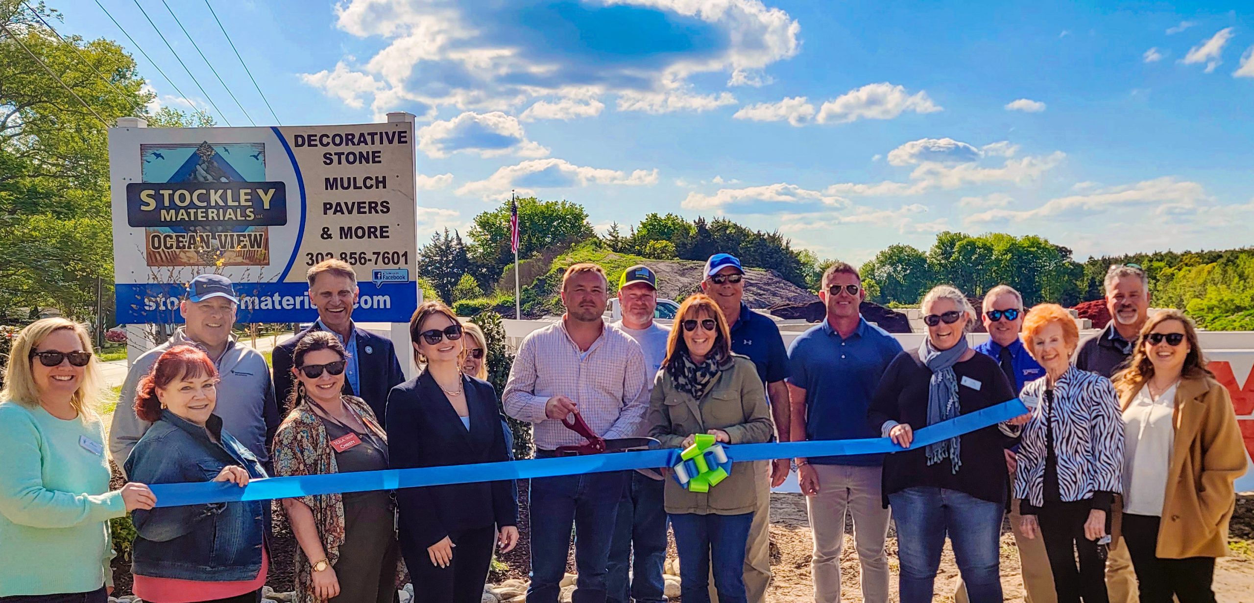 a group of people standing in front of a blue ribbon