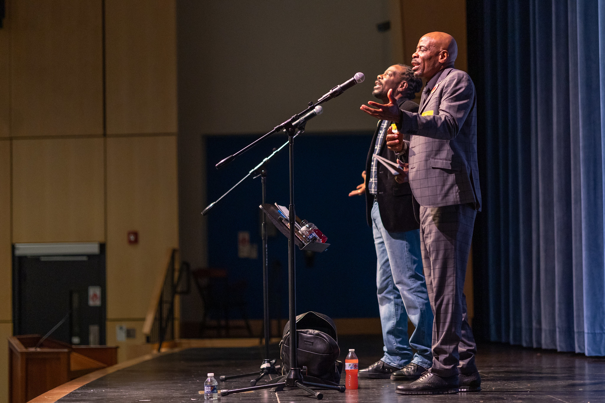 two men standing in front of microphones on a stage