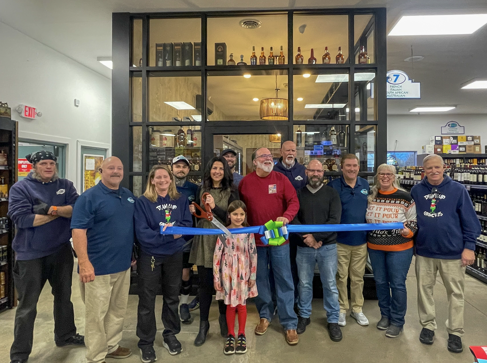 a group of people holding a ribbon in front of a store