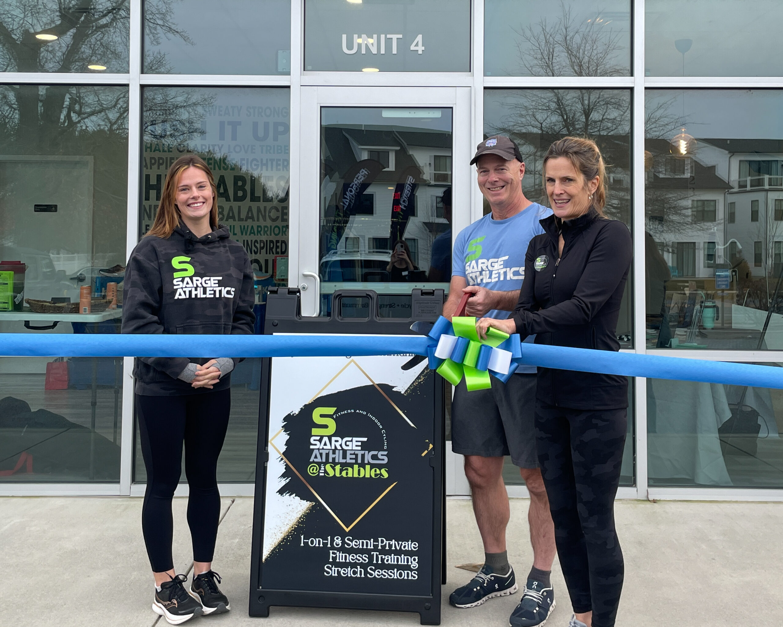three people standing behind a ribbon cutting the ribbon