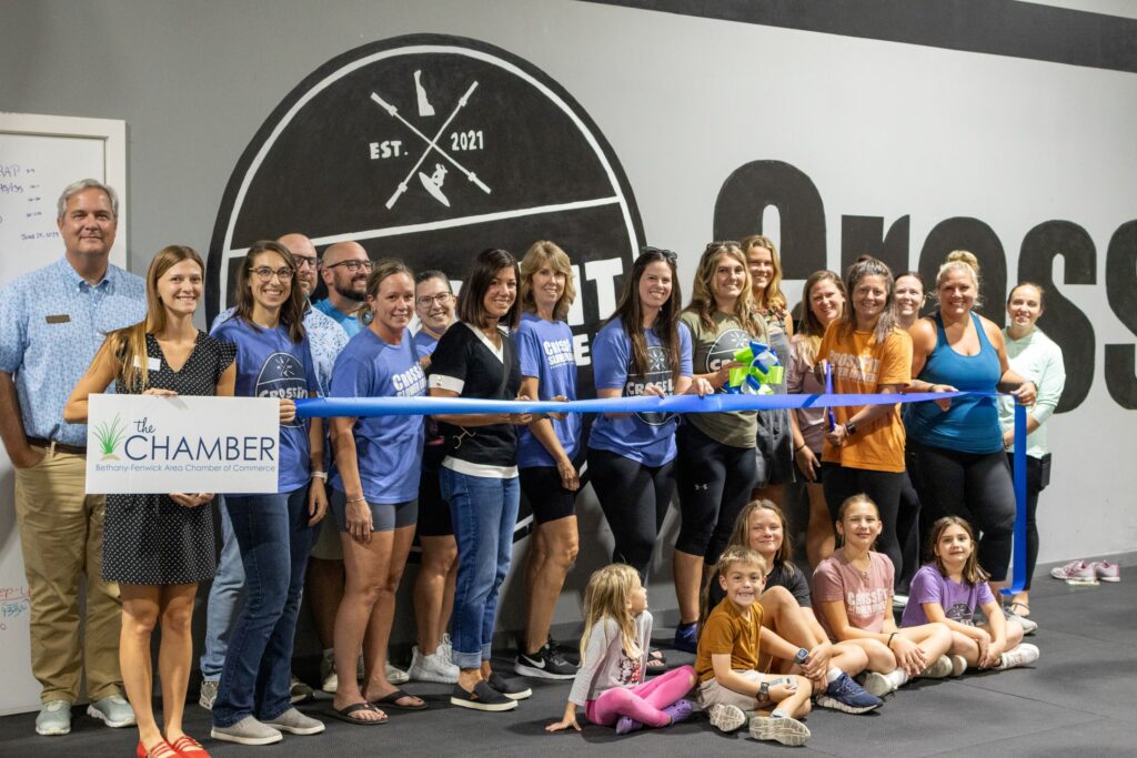 a group of people holding a ribbon at a ribbon cutting ceremony