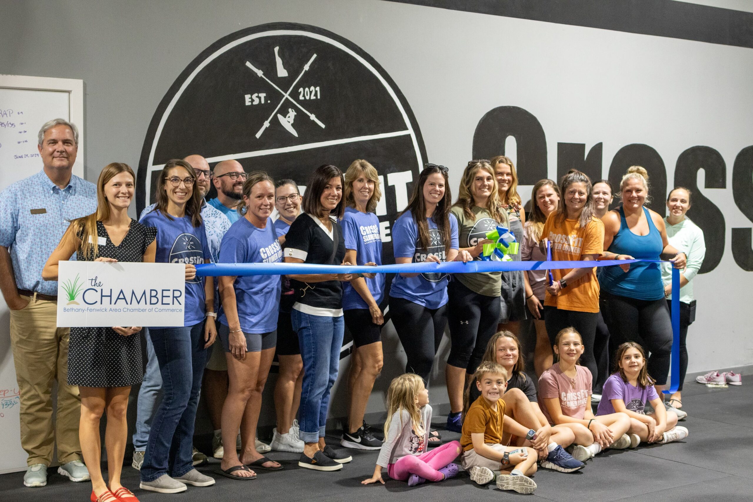 a group of people holding a ribbon at a ribbon cutting ceremony