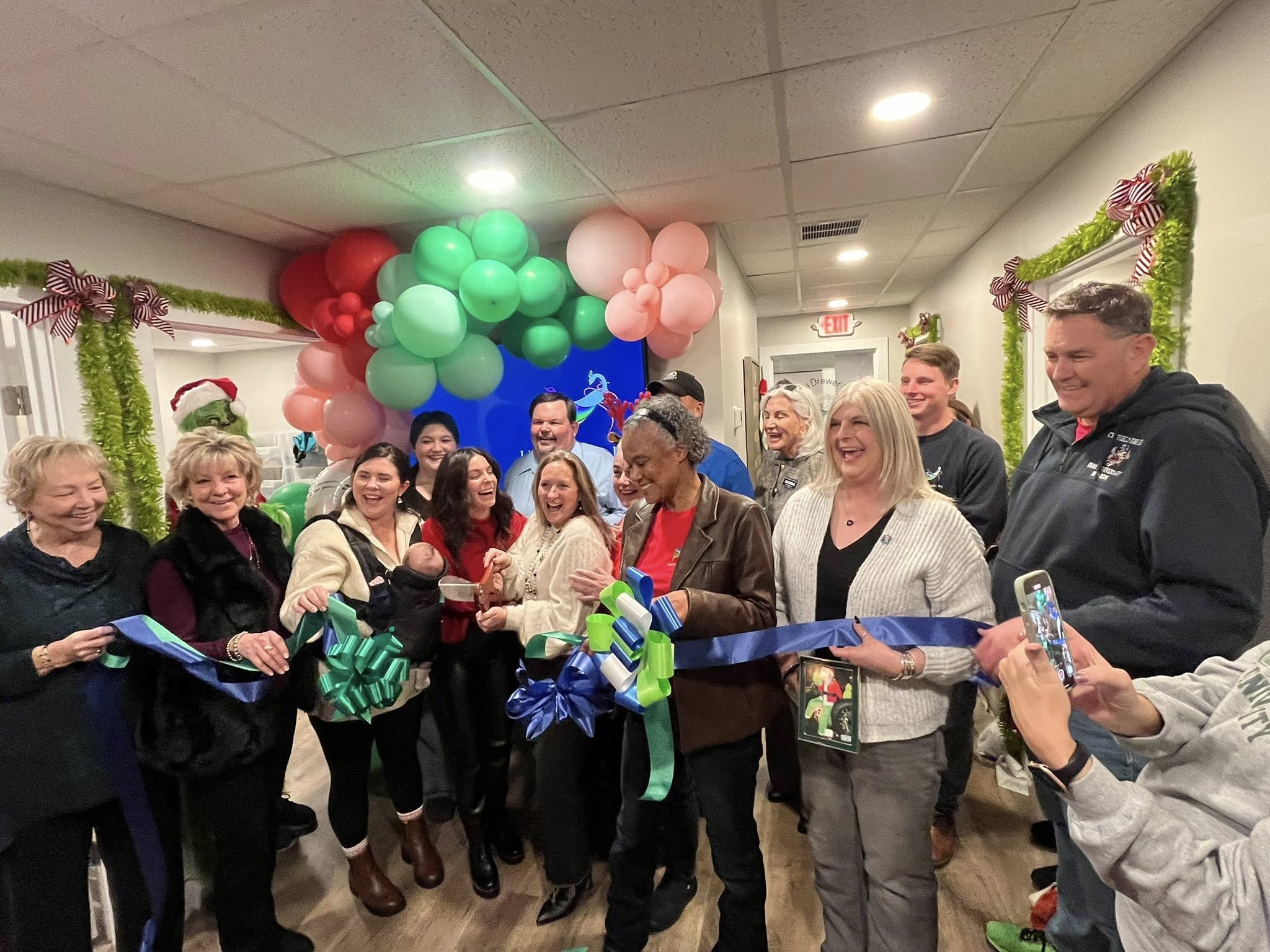 a group of people standing around a ribbon cutting