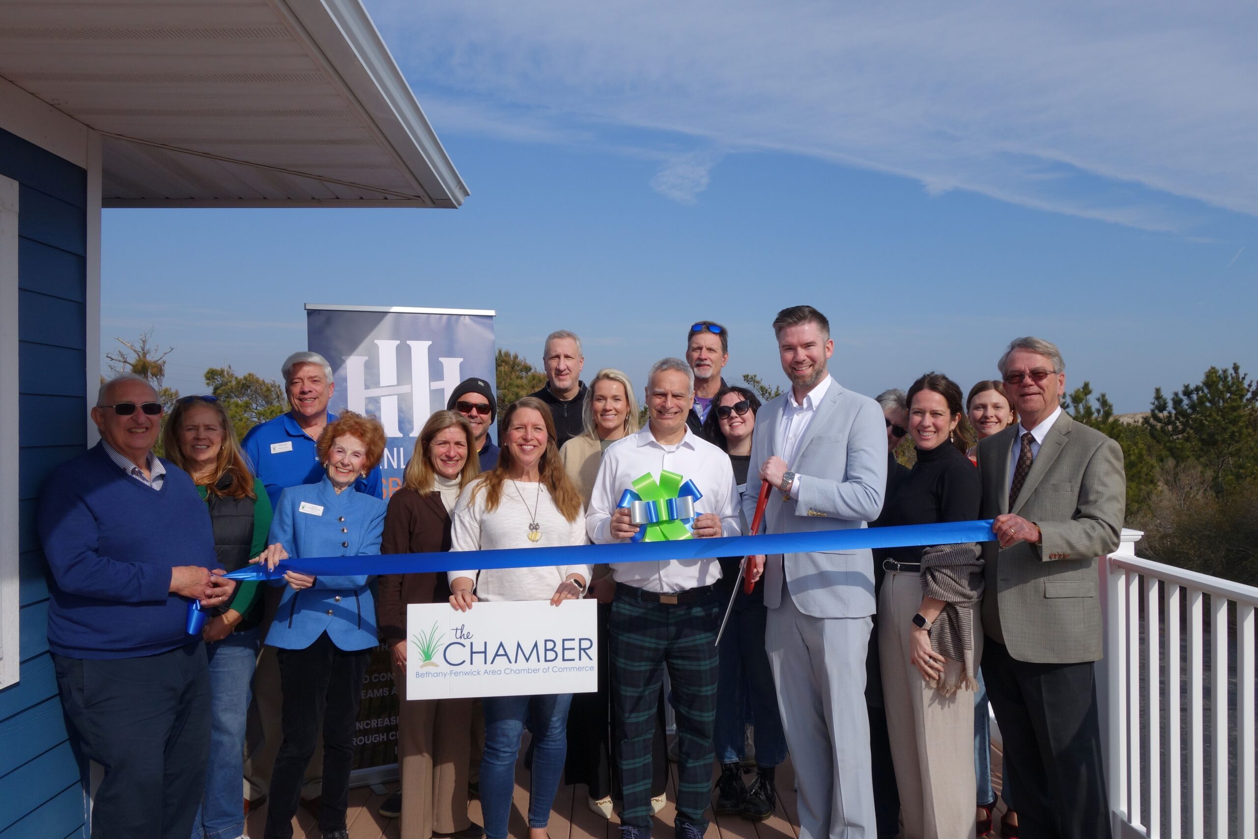 a group of people standing on a porch holding a ribbon
