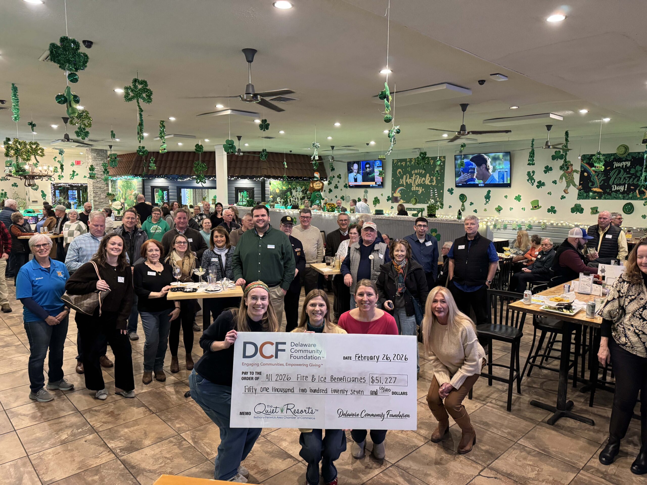 a group of people standing in a room holding a check