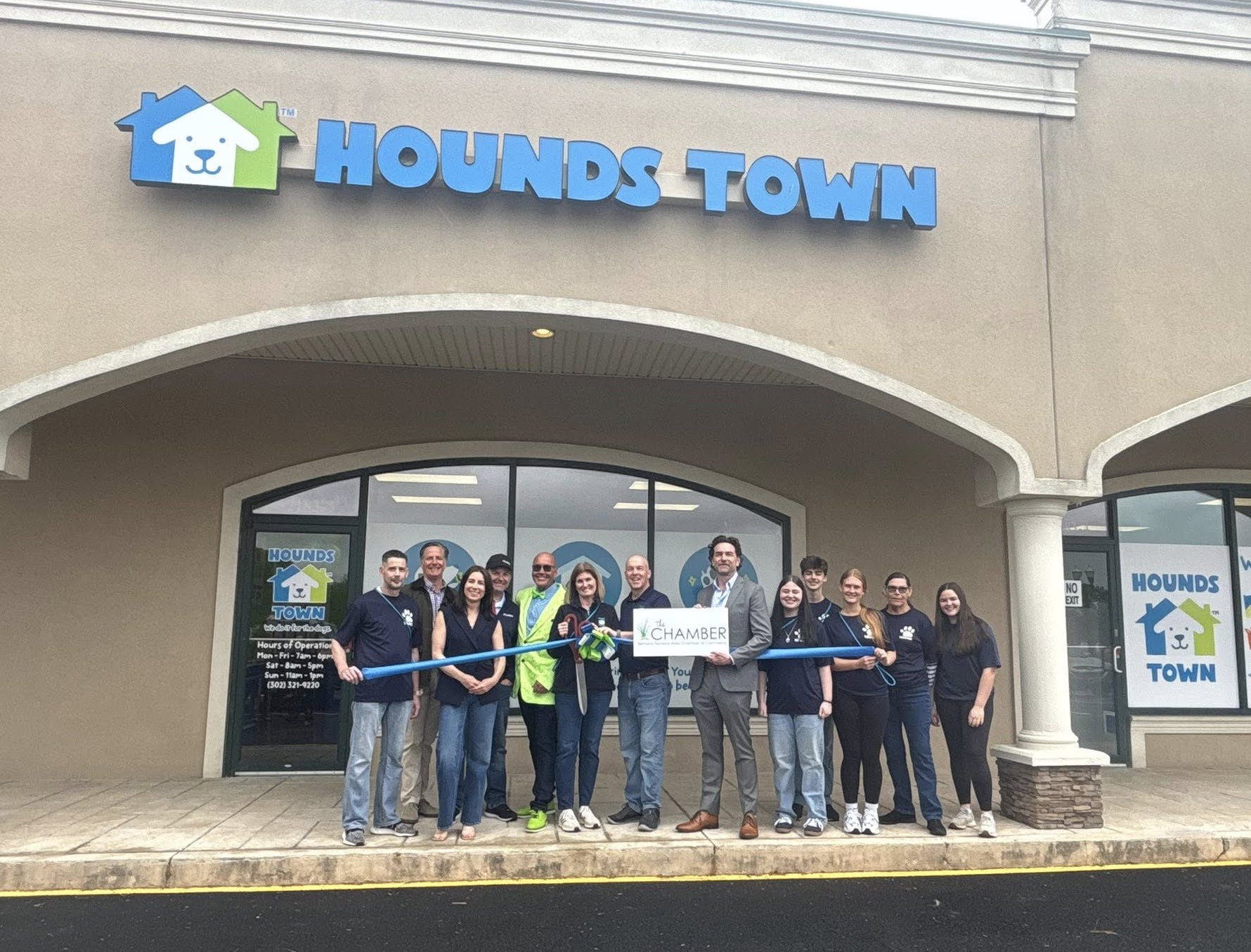 a group of people holding a ribbon in front of a store