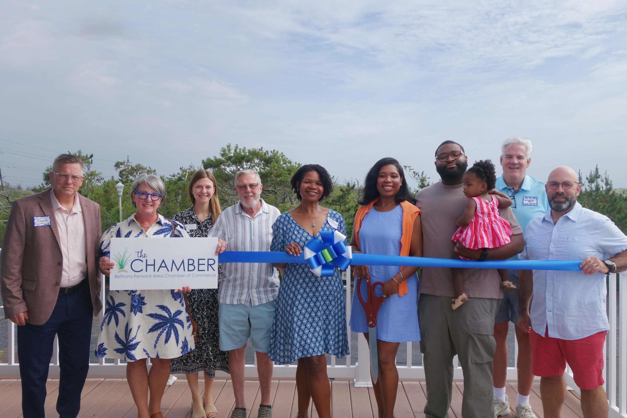 a group of people standing on a deck holding a ribbon
