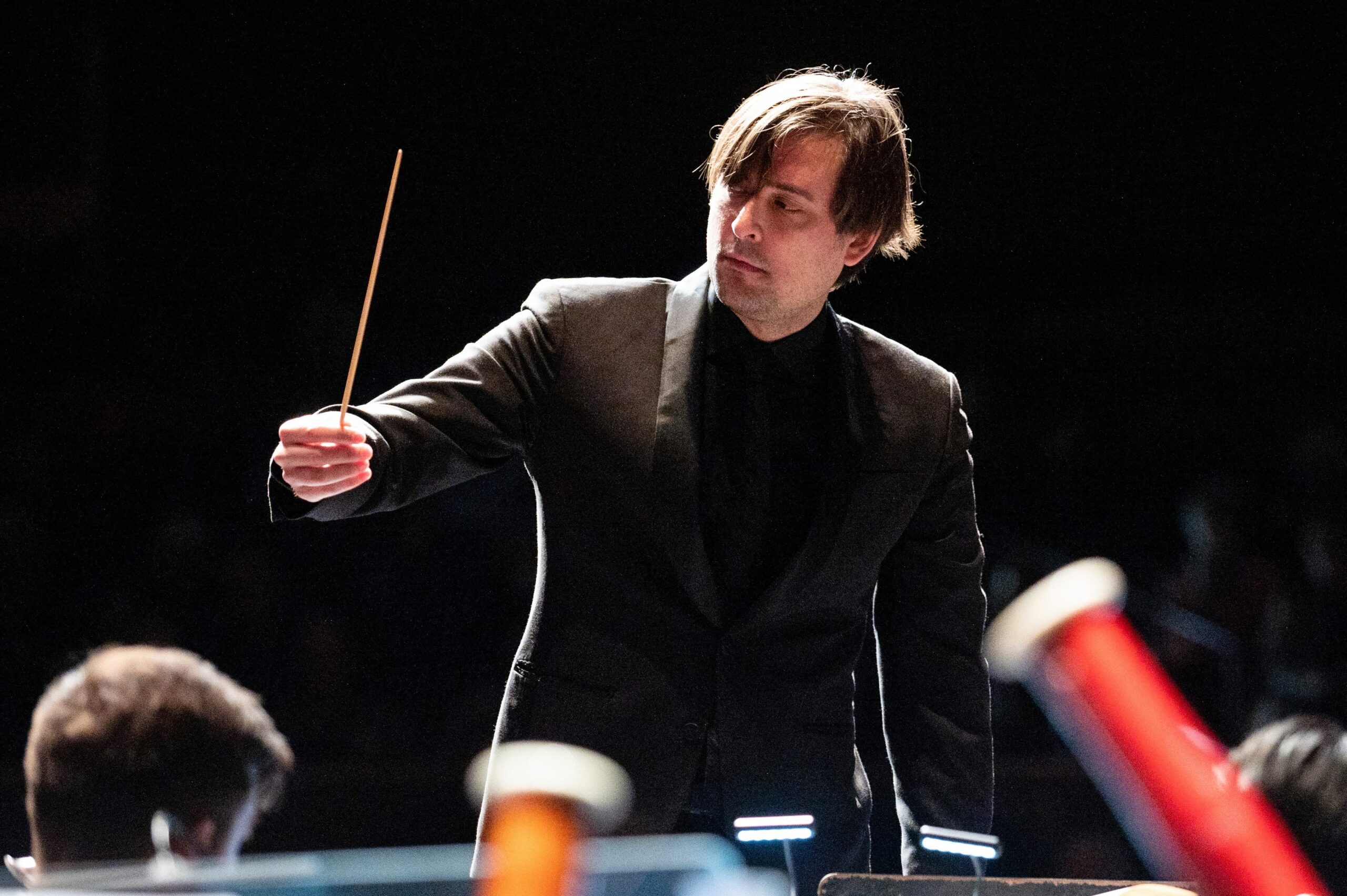 a man in a suit and tie holding a conductor's baton