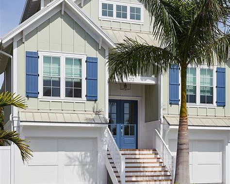 a white house with blue shutters and a palm tree