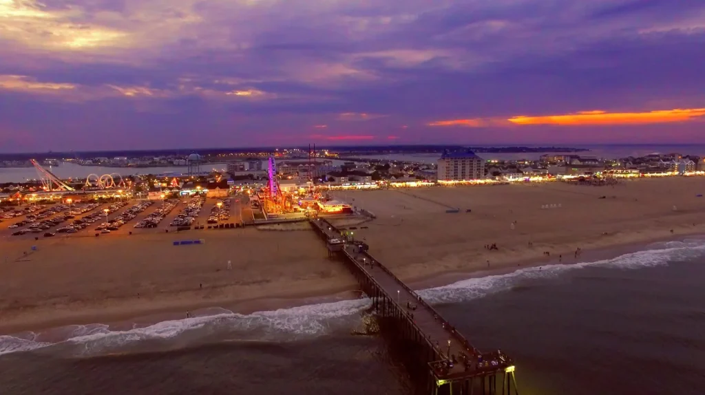 an aerial view of a beach and pier at night
