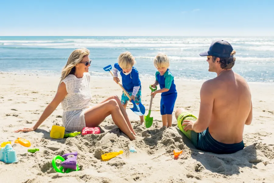a family playing in the sand at the beach