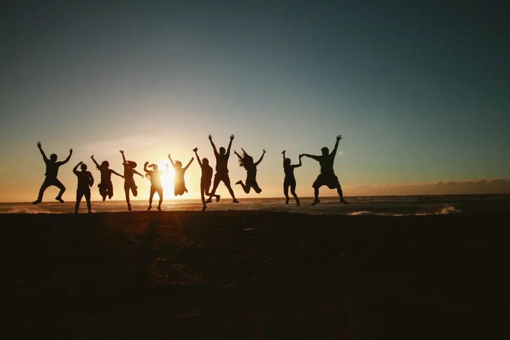 a group of people jumping in the air at sunset