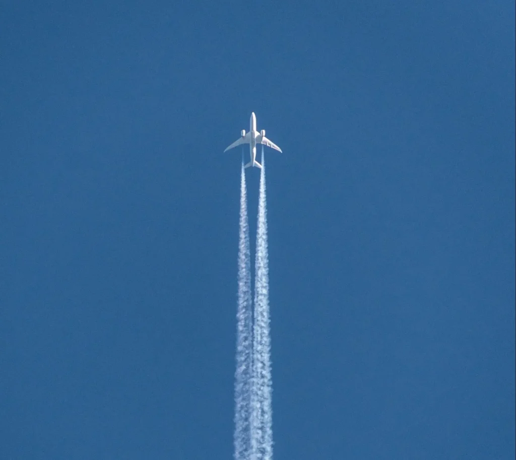 a jet flying through a blue sky leaving a trail of smoke behind it