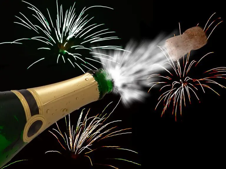 a bottle of champagne being opened with fireworks in the background