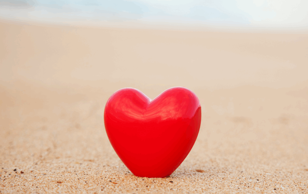 a red heart shaped object on a sandy beach