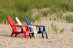 a row of colorful chairs sitting on top of a sandy beach