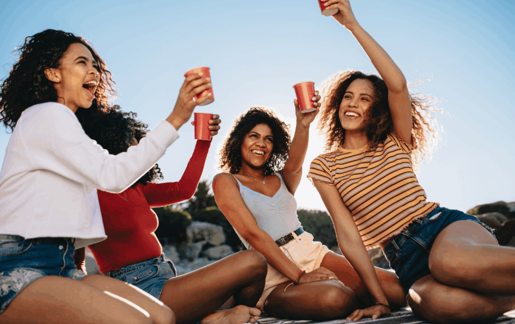 a group of women sitting on top of a beach next to each other