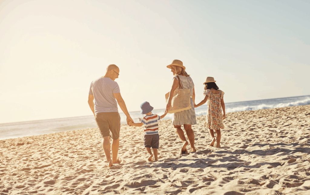 a family walking on the beach holding hands