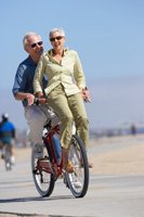 a man and woman riding a bike on the beach