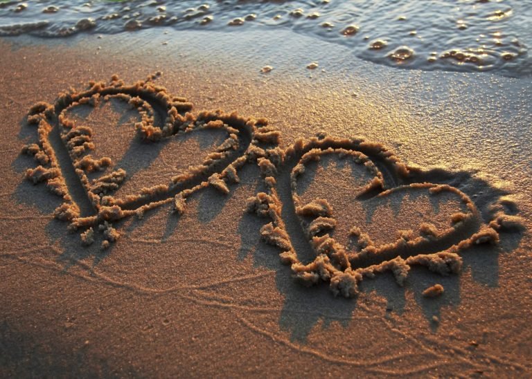 two hearts drawn in the sand on a beach