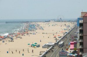 a crowded beach with a ferris wheel in the distance