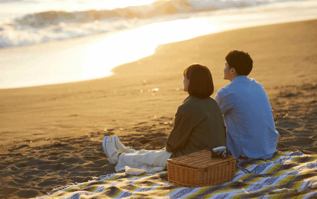 couple sitting on blanket at the beach at sunset