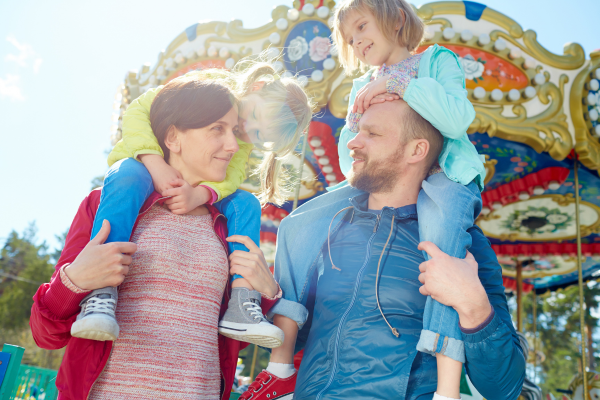 a man, woman and child standing in front of a carnival ride