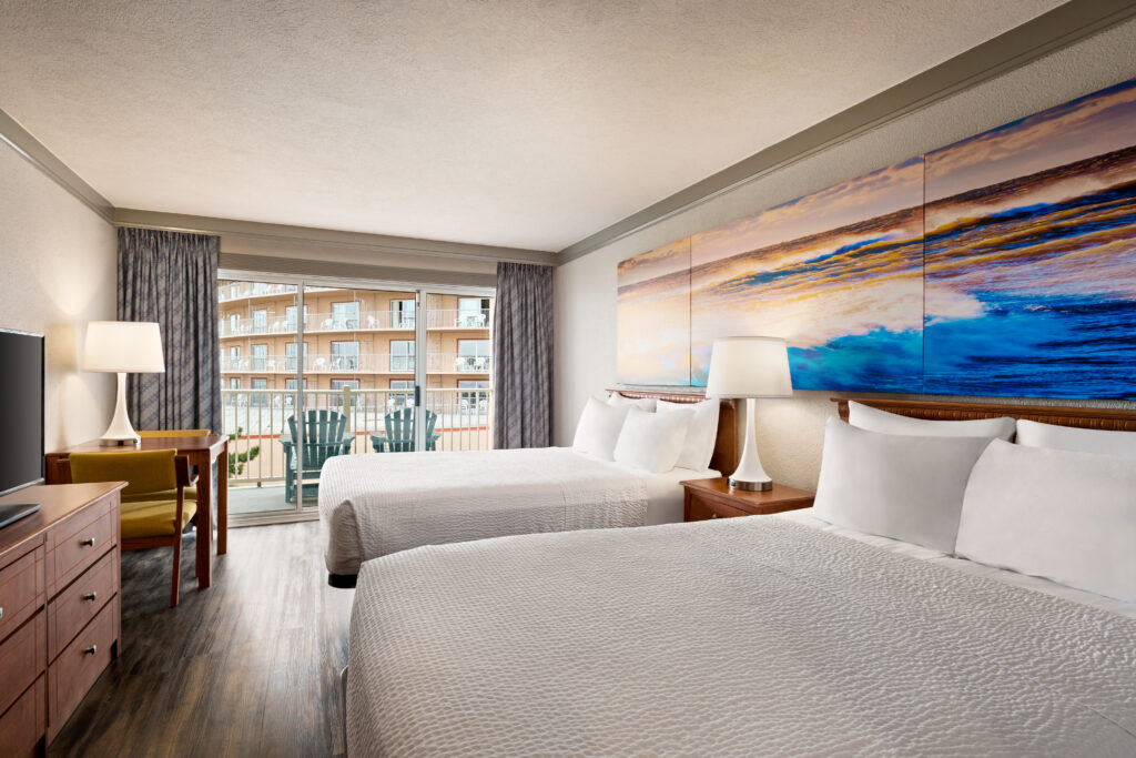 a hotel room with two beds and a flat screen tv