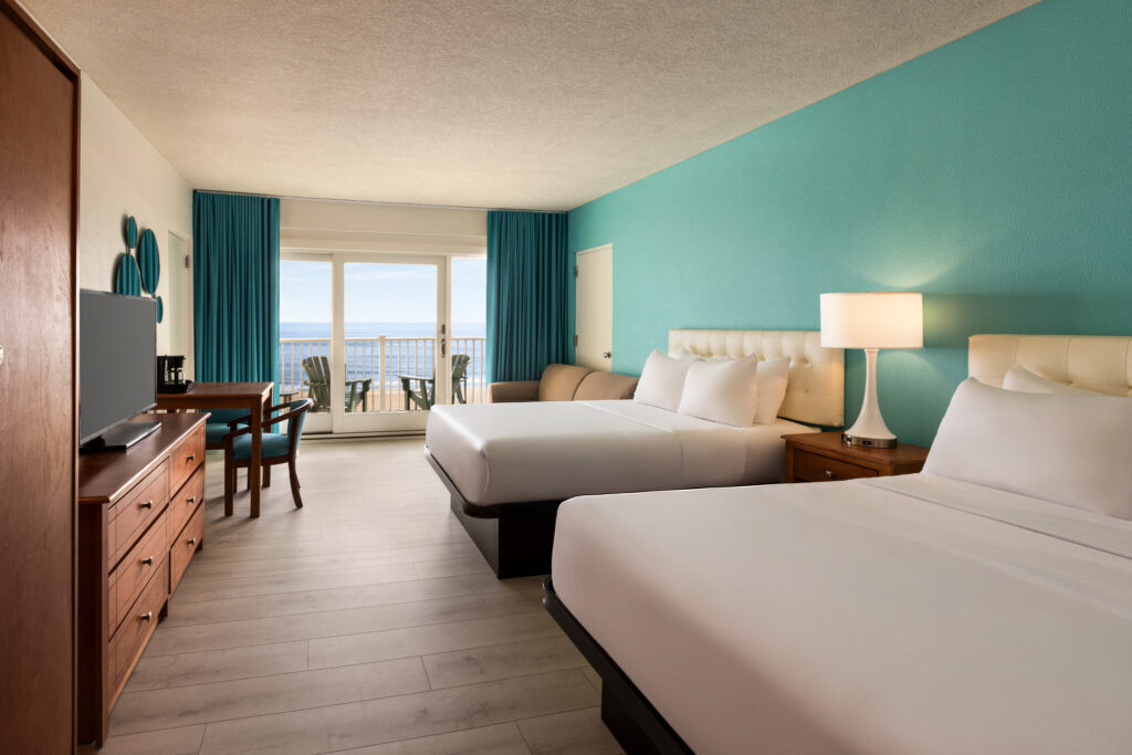 a hotel room with two beds and a flat screen tv