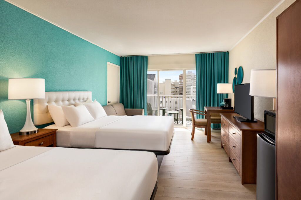 a hotel room with two beds and a flat screen tv