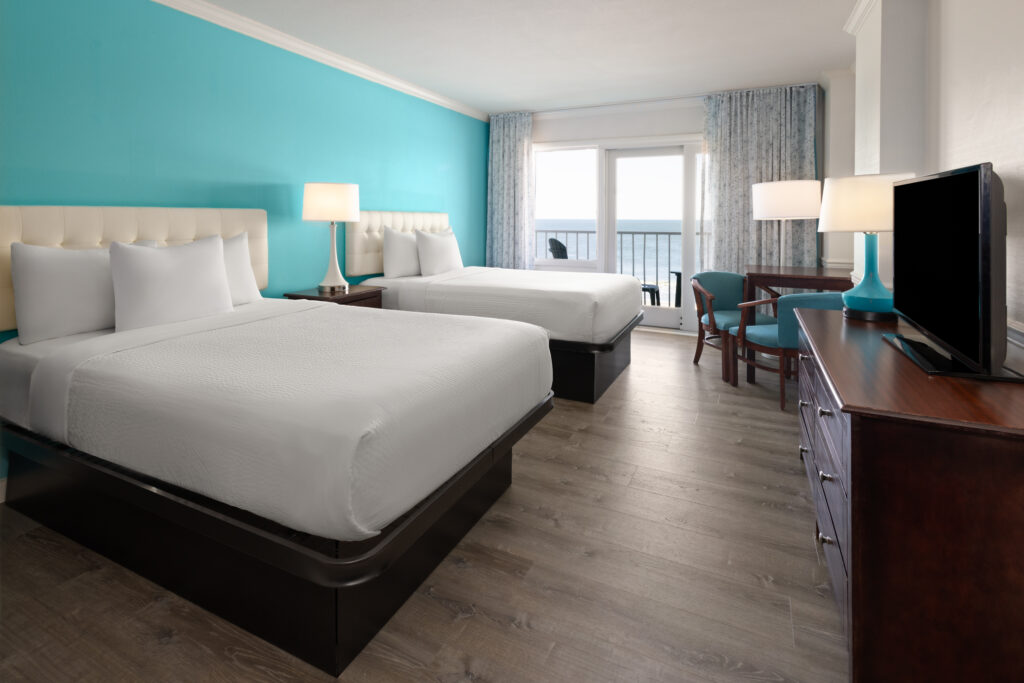 a hotel room with two beds and a flat screen tv