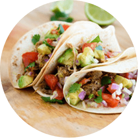 two tacos with meat and vegetables on a cutting board