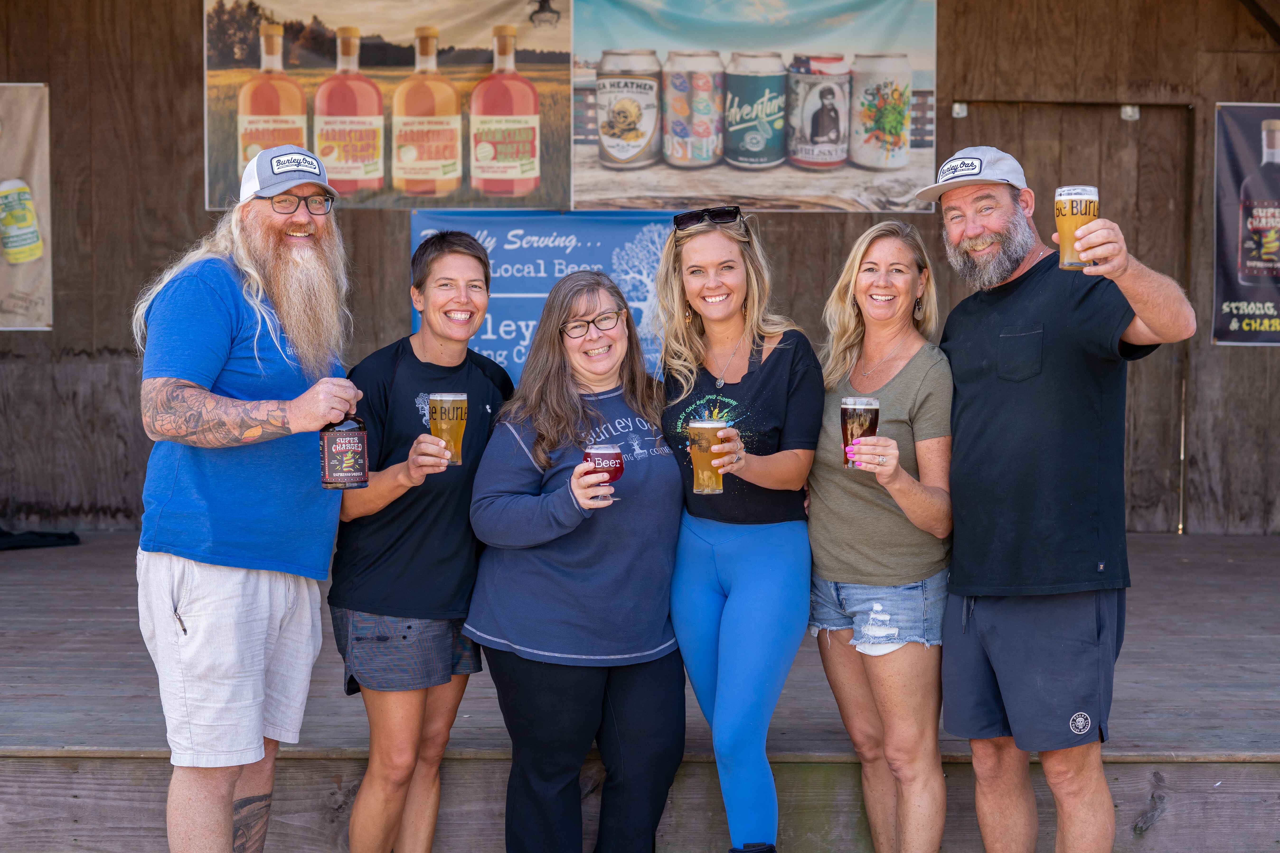 a group of people standing next to each other holding beers