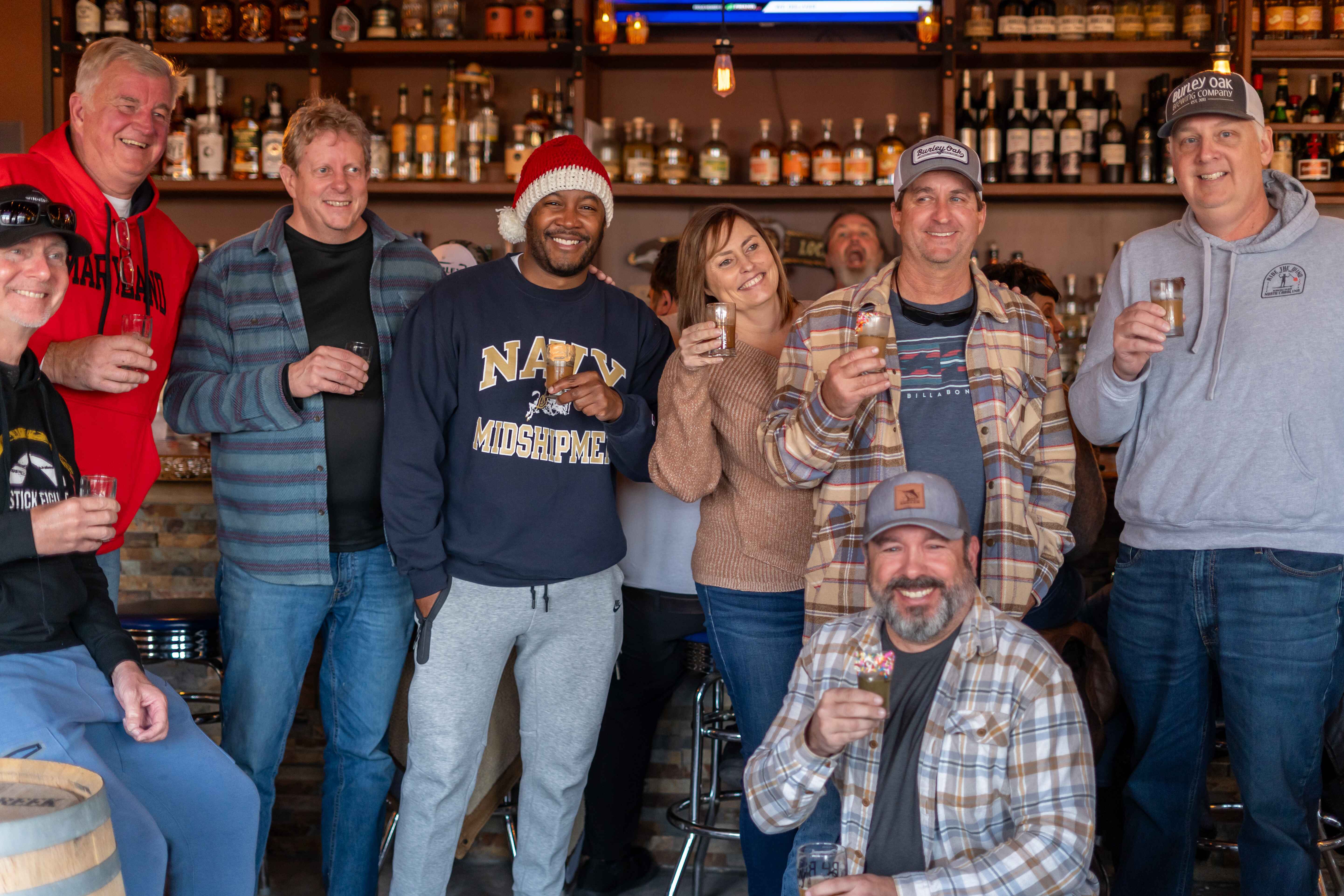 a group of people standing and sitting in front of a bar