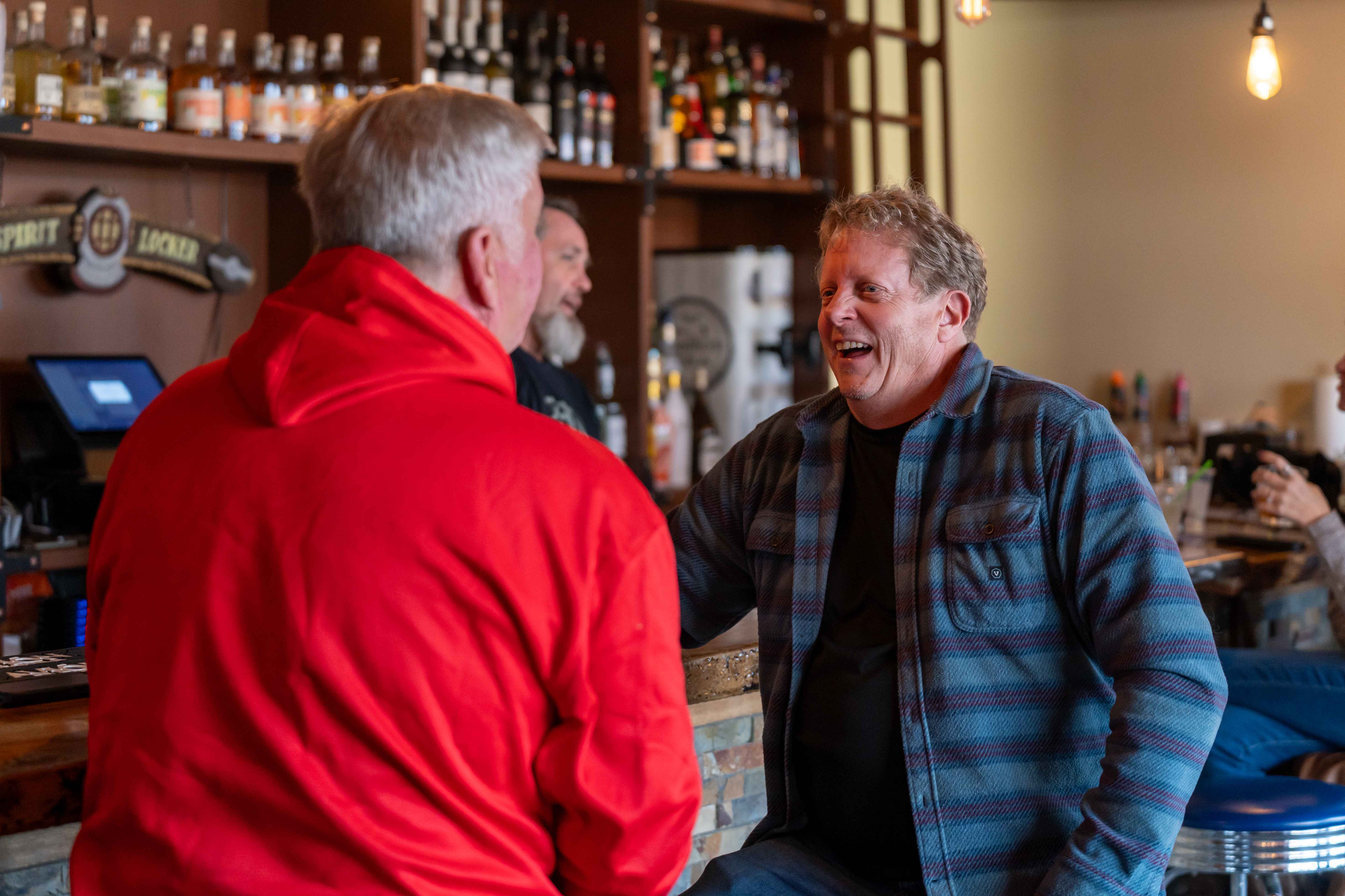 a group of men standing around a bar talking
