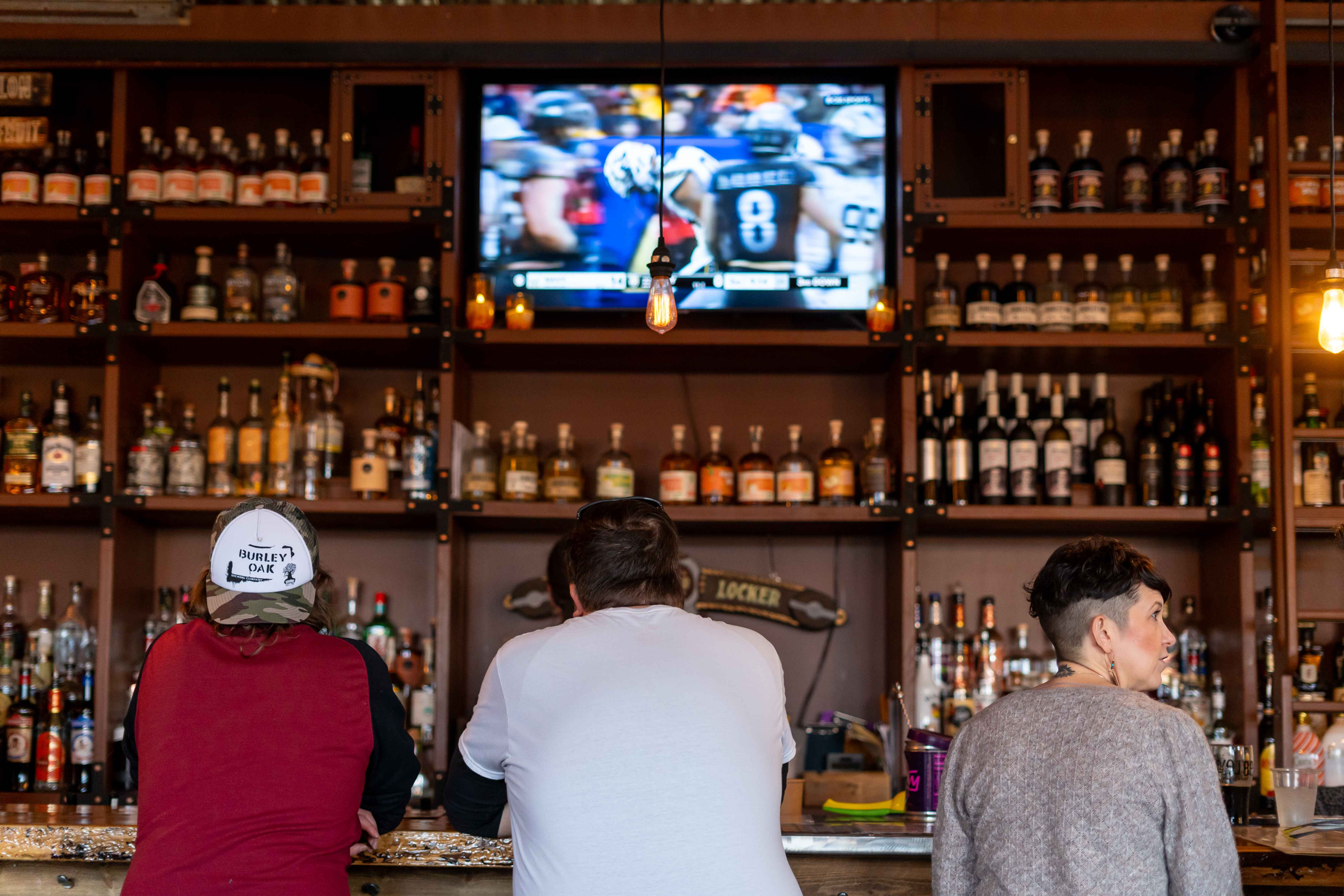 a group of people sitting at a bar watching tv