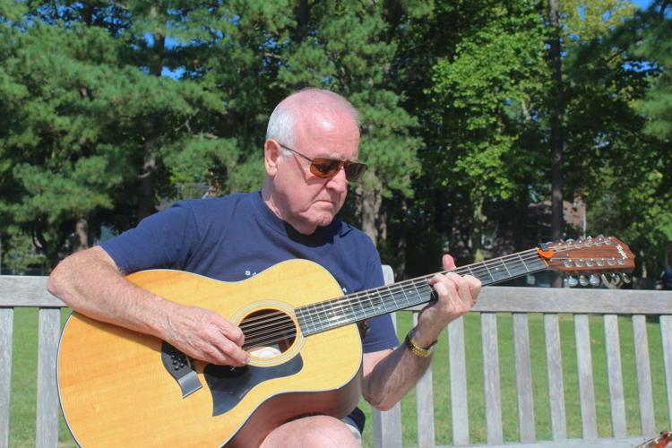 a man sitting on a bench playing a guitar