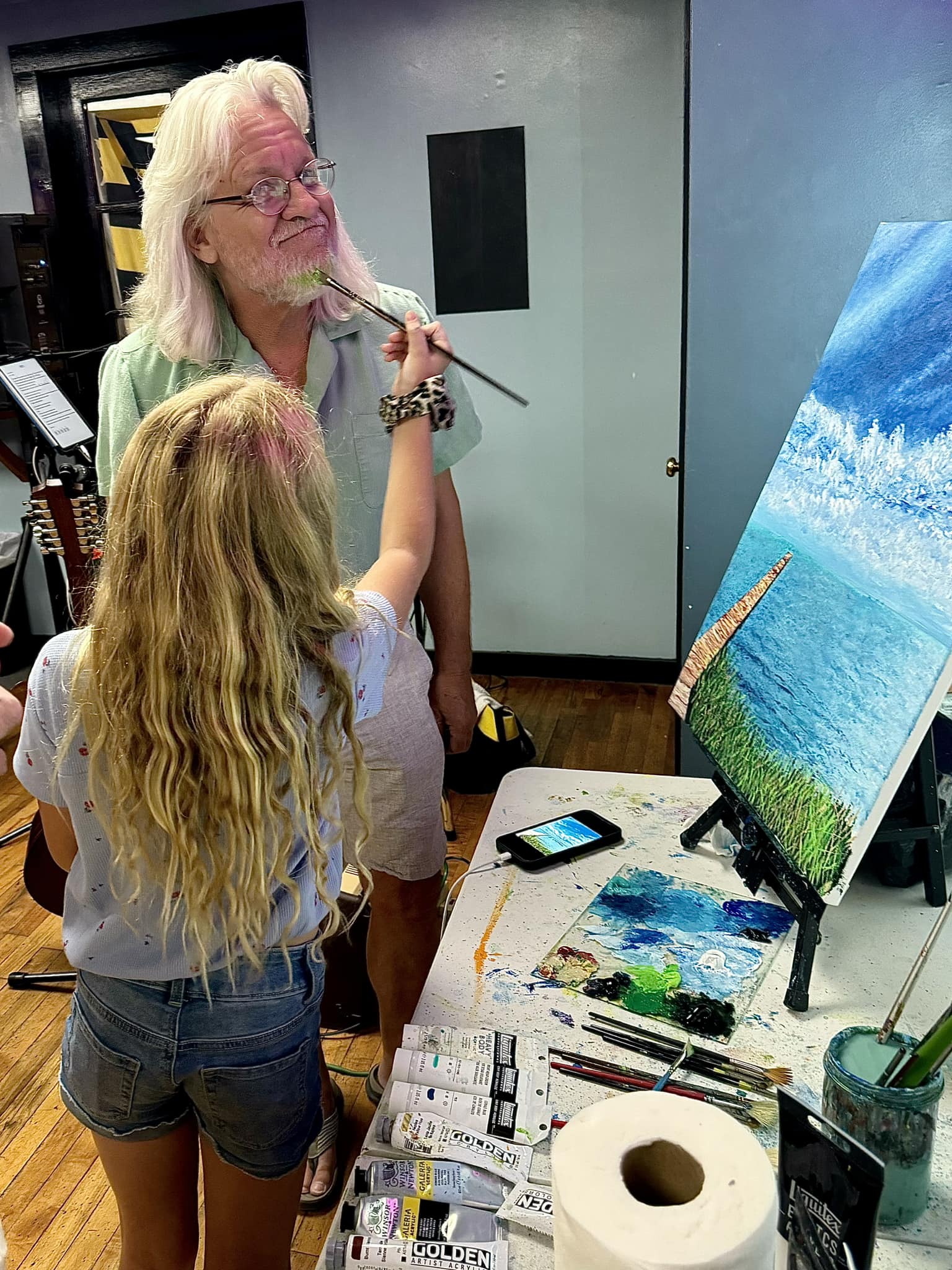 a group of people standing around a table with a painting on it
