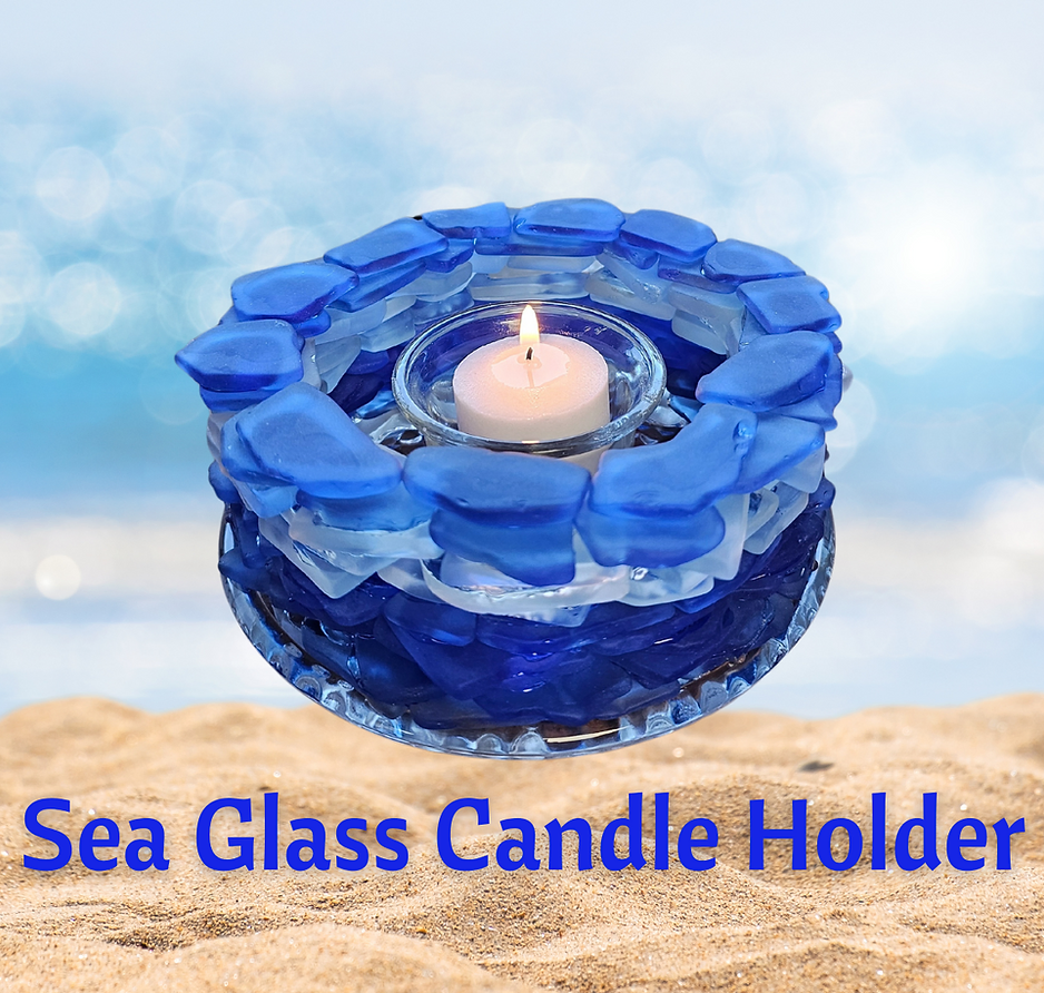 a blue glass candle holder sitting on top of a sandy beach