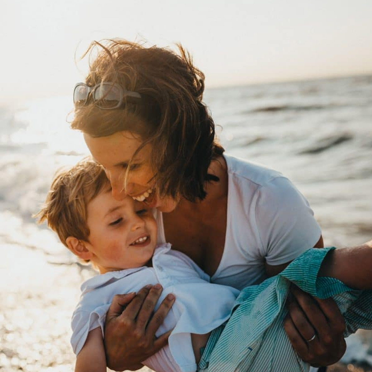 a woman holding a child on the beach