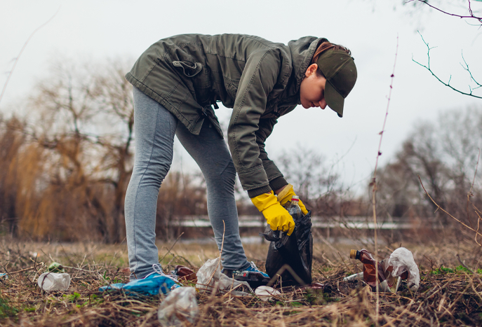 Young person picking up garbage outside