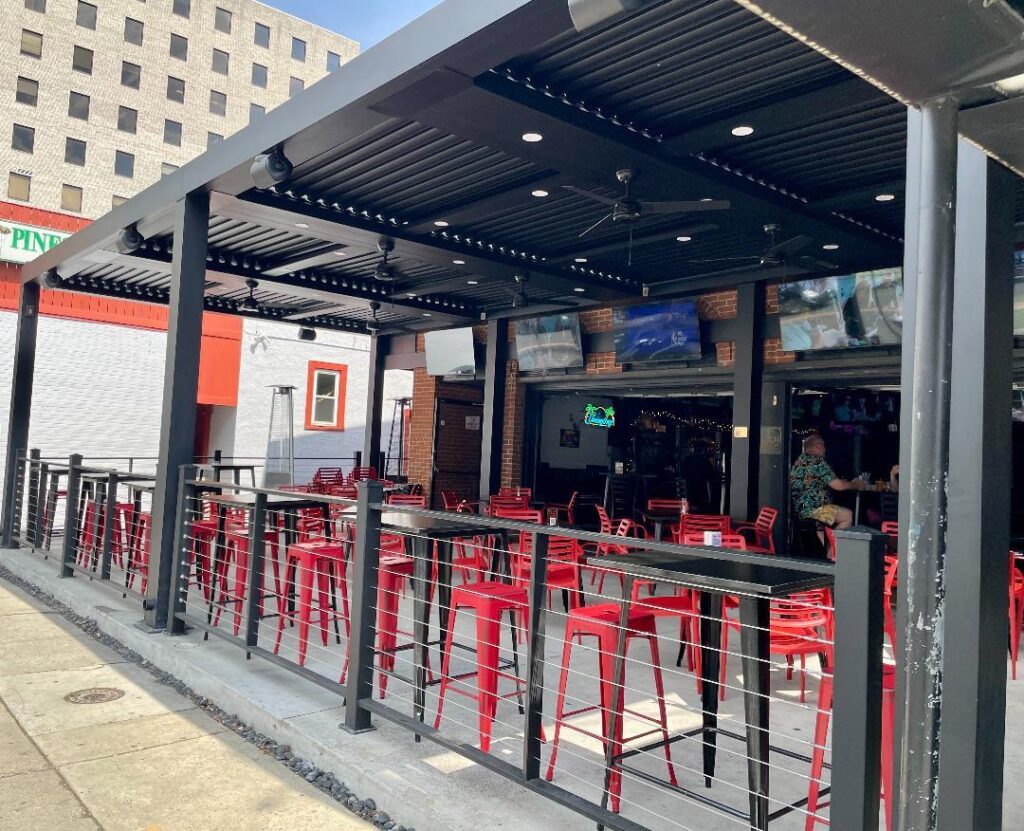 the outside of a restaurant with red chairs