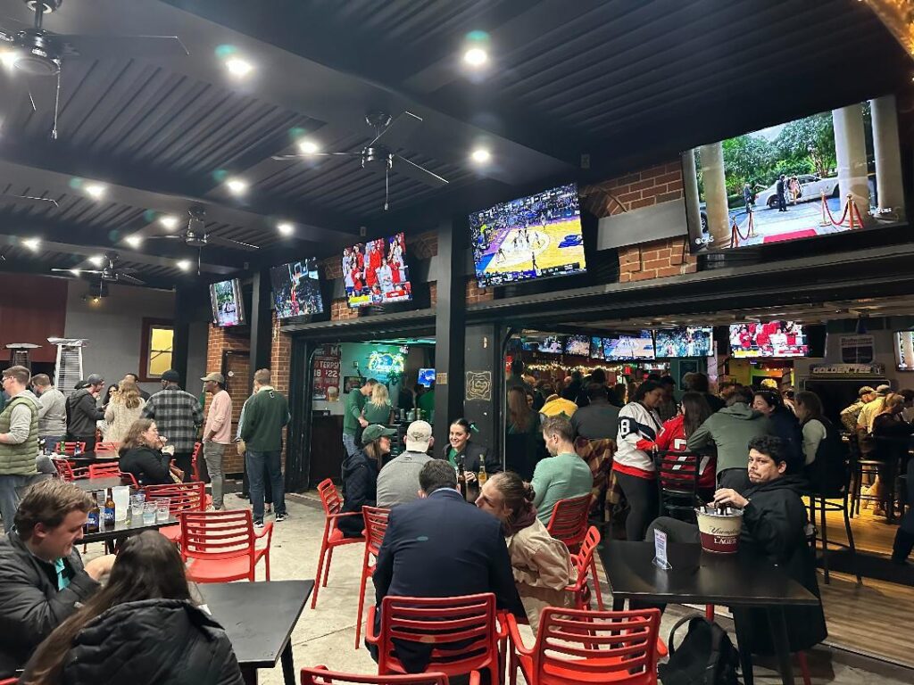 a group of people sitting at tables in a sports bar