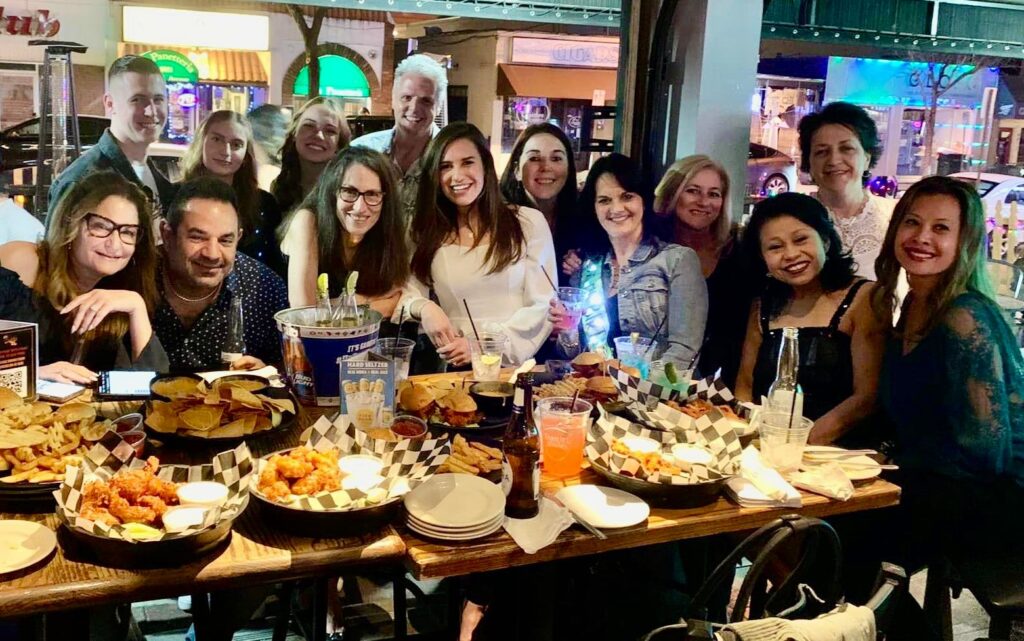 a group of people are posing for a photo at a table full of food