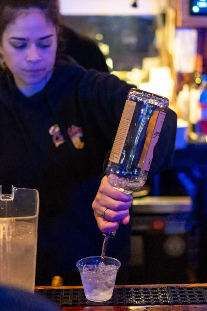 a woman pouring a drink into a glass