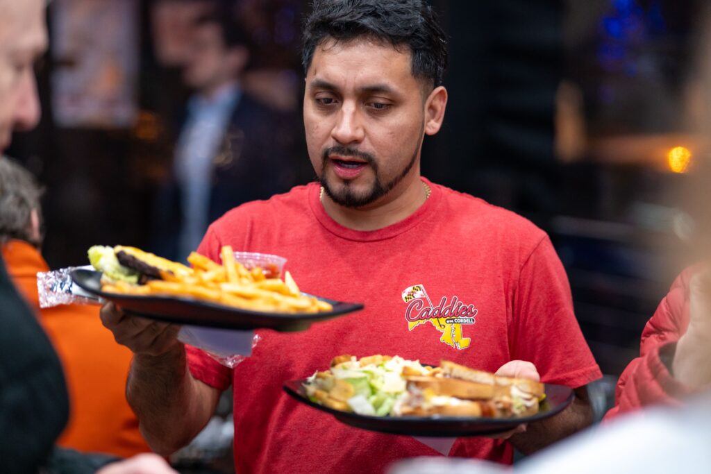 a man in a red shirt holding two plates of food