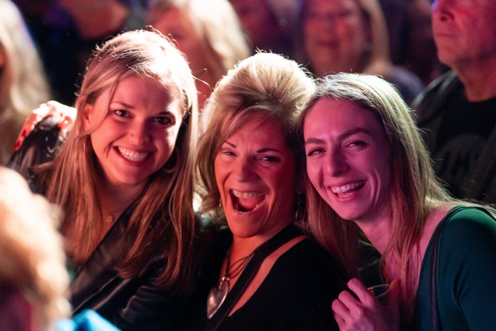 three women are posing for the camera in front of a crowd