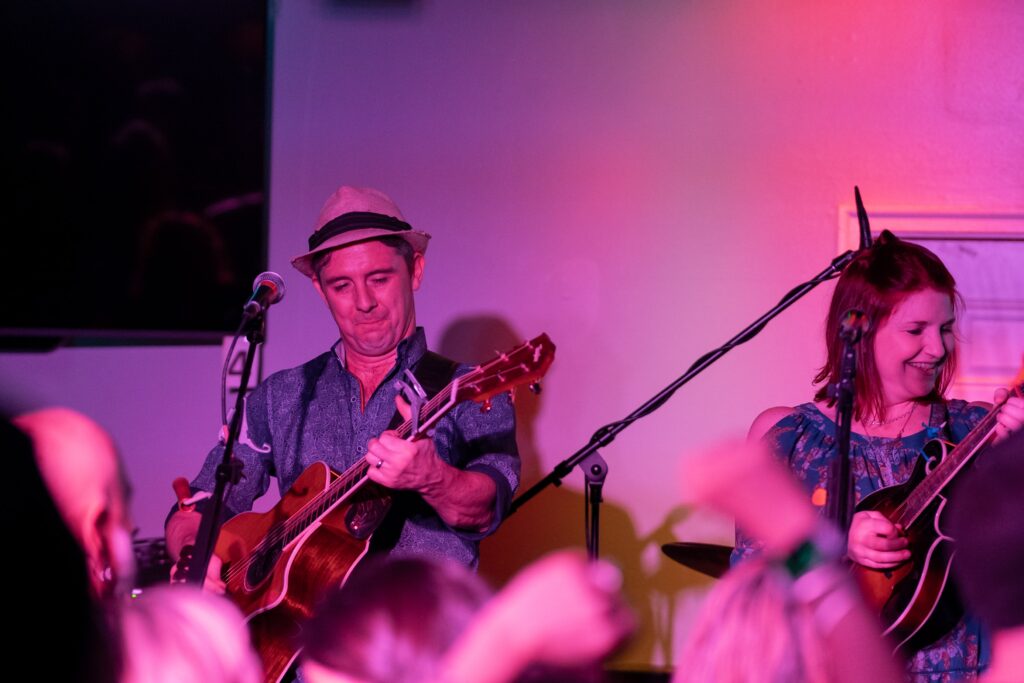 a man and woman playing guitars in front of a crowd