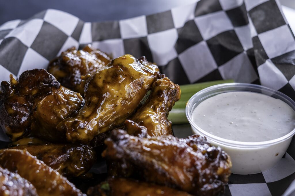 a plate topped with chicken wings next to a bowl of ranch dressing